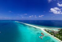 Stunning aerial view of a tropical island in the Maldives with pristine beaches and clear blue waters.