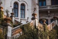 Historic villa exterior with ivy-clad stone staircase and potted plants.