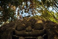 prasana bali A monkey sitting on an ornate sculpture in Ubud's lush monkey forest.
