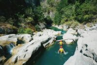Two adventurers tubing through a scenic river canyon in Nusa Tenggara, Indonesia.