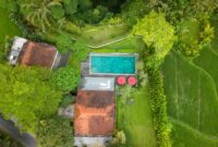 Aerial shot of a beautiful villa with a pool surrounded by lush greenery in Bali, Indonesia.